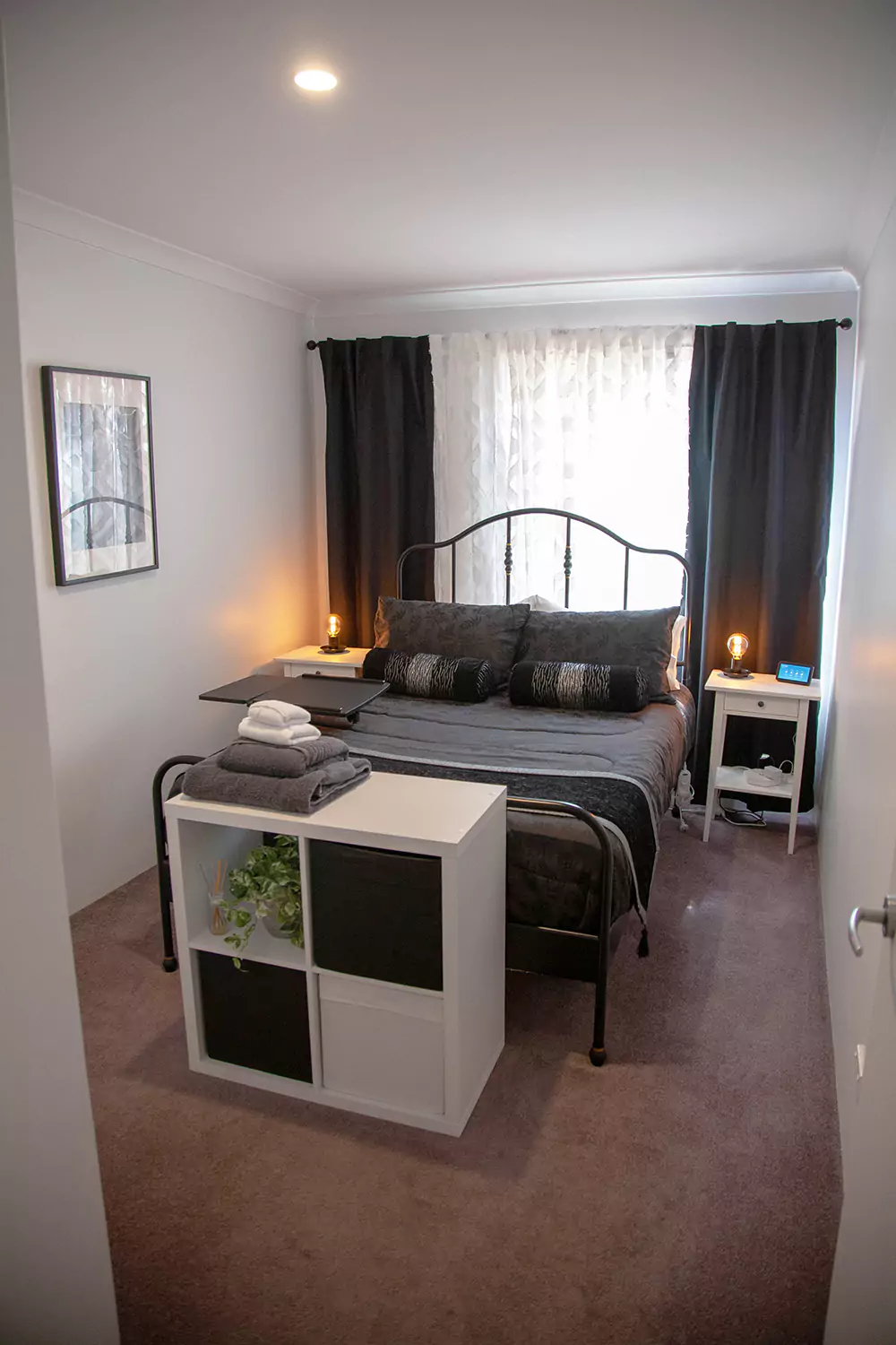 The image shows the second bedroom of the Sudden Comfort's accommodation. There are clean towels folded at the foot of the bed and warm inviting lamps on the bedside tables.